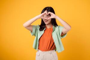 healthcare and wellness guided by an Asian woman in her 30s. Let her heart hand gesture on a vibrant yellow background inspire your journey towards body wellness photo