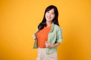 radiance of happiness and well-being with a cheerful young Asian woman 30s wearing an orange shirt. Her happy mind wellness gesture on yellow background reflects a captivating happiness portrait. photo