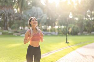 joy and beauty of a fit, happy 30s Asian woman in sportswear as enjoys a refreshing sunset run in nature. A silhouette against sunset creates a stunning sight. Fitness, health, and motivation concept. photo