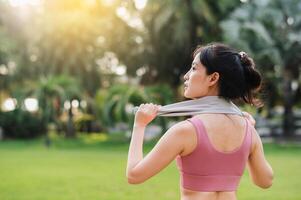 cerca arriba ajuste hembra persona que practica jogging como un asiático mujer en su 30, vistiendo rosado ropa de deporte, calienta abajo después un puesta de sol correr en un público parque. abrazo el concepto de bienestar vivo y naturaleza. foto