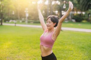 alegría de un feliz, ajuste hembra persona que practica jogging en su 30 años asiático mujer vistiendo rosado ropa de deporte, disfrutando Fresco aire en un público parque. abrazo bienestar vivo y conectar con naturaleza. foto