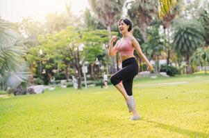 wellness and well-being fit 30s Asian woman, wearing pink sportswear, exercising in a public park at sunset. Embrace a healthy outdoor lifestyle and discover the benefits of wellness and well-being. photo