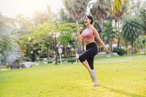 concept of wellness and well-being fit 30s Asian woman wearing pink sportswear exercising in public park at sunset. healthy outdoor lifestyle, wellness and well-being. photo
