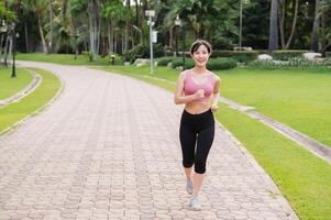 Woman jogger. back perspective portrait of young asian female wearing pink sportswear running in public park. Healthcare wellness concept. photo