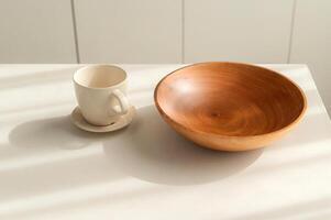 paso dentro elegante y limpiar cocina con Clásico encanto. sencillo y brillante, redondo de madera vajilla y utensilios crear todavía vida de sencillez. mano hecho café taza y bol. foto