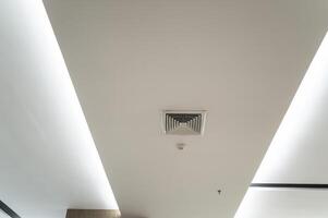 Ceiling mounted cassette type air conditioner and modern lamp light on white ceiling. Duct air conditioner for home, hall or office. photo