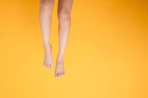 Immerse in the elegance of smooth and soft touch with 30s person's close up legs on vibrant yellow background. Gentle and velvety foot concept. photo