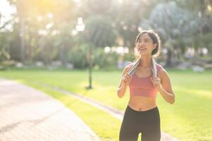 belleza de un ajuste y contento 30s joven asiático mujer en ropa de deporte, disfrutando un refrescante puesta de sol correr en naturaleza. aptitud física, salud y motivación ese cautivador silueta en contra el ajuste Dom trae. foto