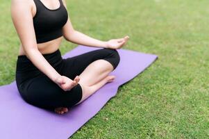 Serene Yoga Journey. Balanced on a lotus pose, a woman practices yoga amidst the tranquil greenery of the jungle, embracing nature's serenity. photo