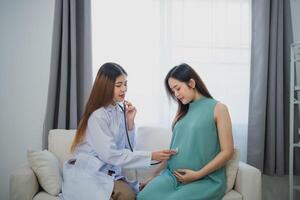 Asian professional woman doctor using stethoscope listening to belly pregnant woman. Medical exam pregnant woman. Healthcare in examination room at hospital or clinic. photo