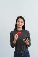 Asian woman holding showing credit card and mobile phone to shopping online isolated on white or gray background studio. Online shopping, e-commerce, internet banking, spending money concept. photo