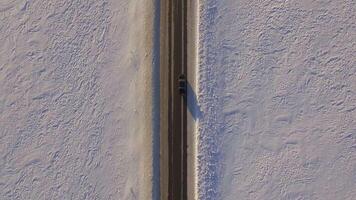 Suv rides on road through the snowy field. Aerial view on a snowy field and road from quadrocopter. Aerial view of snowy fields and road video