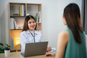 asiático profesional mujer médico hablando consultar para cuidado de la salud solución a su paciente o embarazada mujer en examen habitación a hospital o clínica. foto