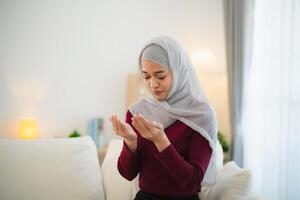 musulmán islam mujer con hijab hacer un día orar ese espectáculo su creer en dios. musulmán mujer Orando en el vivo habitación a hogar. foto