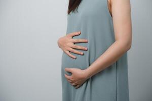 mujer embarazada sosteniendo su vientre haciendo forma de corazón de mano aislada sobre fondo blanco. madre de familia mamá concepto embarazada. foto