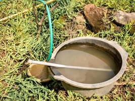 black bucket filled with murky water on the edge of a rice field photo