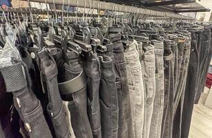 Grey and black jeans on the hangers in the clothes shop. Black denims in the shop. Trousers. photo