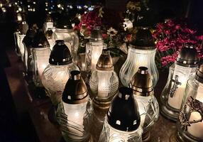 tumba velas en el tumba durante el todas santos día. cementerio velas con hermosa luces y flores cementerio durante el todas almas día. foto