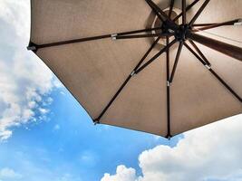 Low angle view of an opened beach fabric umbrella against the blue sunny sky, view from under parasol, holiday or vacation concept, with copy space photo