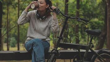 Relajado y relajado joven asiático mujer en casual confortable ropa montando un bicicleta en el bicicleta carril en el parque. pasatiempo y ejercicio concepto video