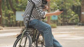 chilling e rilassato giovane asiatico donna nel casuale comodo Abiti equitazione un' bicicletta su il bicicletta corsia nel il parco. passatempo e esercizio concetto video