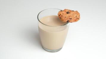 chocolate chip galletas y un vaso de Leche café en un blanco antecedentes foto