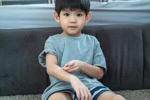 Little Asian boy's hands peeling off dry skin on his arm. Skin problems. photo