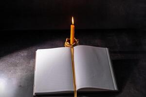 Yellow candlestick gives light while reading, black background photo