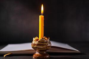 Yellow candlestick gives light while reading, black background photo