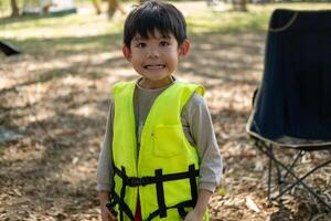 A little Asian boy puts on a life jacket and prepares to play in the water. photo