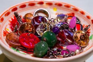 Closeup photo of many necklaces and earrings in various colors on a small bowl