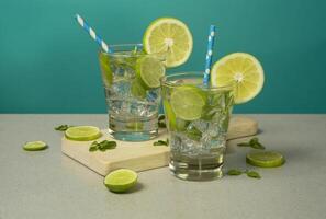 Two cocktails in glass glasses filled with ice and lemon slices garnished with lemon slices and sorbets on a wooden board photo