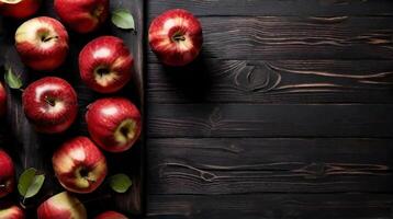 ai generado maduro jugoso rojo manzanas son dispersado en negro de madera tablero. espacio para texto. foto