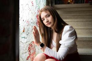 Portrait of Teenage girl looking through the window at a graffiti on the wall. photo