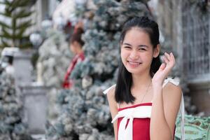 Portrait of teenage girl in a red dress relaxed and smiling in a snowy yard. photo