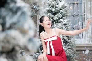 retrato de Adolescente niña en un rojo vestir relajado y sonriente en un Nevado patio trasero. foto