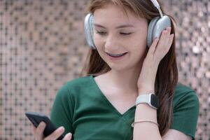 retrato de Adolescente niña escuchando a música con auriculares y móvil teléfono. foto