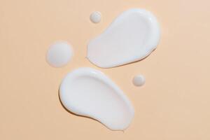 crema para el cuidado de la piel, suero facial, muestra de loción sobre fondo beige. producto de belleza cosmético cremoso de luz blanca mancha deslizar primer plano foto