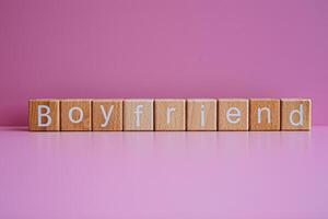 Wooden blocks form the text Boyfriend against a pink background. photo
