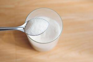 1 tablespoon sugar on a jar with a wooden background. photo