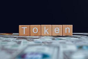 Wooden blocks with the text Token on a black background and crypto banknotes scattered on the ground. photo