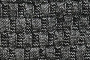 Background with gray knitted leaf shape, knitting pattern with cables. Top view, close-up. Handmade knitting wool photo