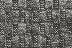 Background with gray knitted leaf shape, knitting pattern with cables. Top view, close-up. Handmade knitting wool photo