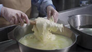 cerca arriba de masculino manos preparando y amasar el masa en bol. escena. cocinero amasadura masa en metal cuenco con agua, oscuro antecedentes. amasadura el masa video