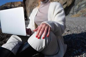 joven hermosa mujer trabajando en un ordenador portátil sentado en el playa foto