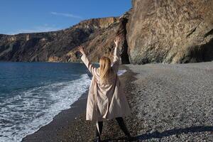 a young beautiful woman runs along a pebble beach against the backdrop of sea photo