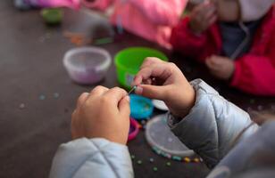 little children's hands weave a bead bracelet close-up shot photo