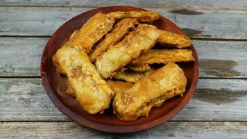 Indonesian traditional meal named tempe goreng. fried fermented soybean cake served in a wooden plate photo