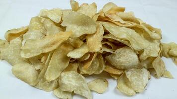 A bowl of sweet taro fried chips or Keripik Talas on a square pattern napkin and white background. Popular indonesian traditional snack. Selective Focus. photo