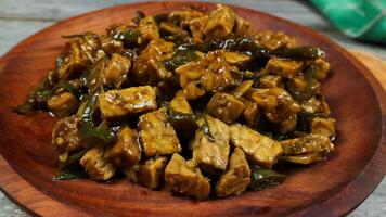 Orek tempe or Sauteed Tempe is a typical Indonesian cuisine with herbs, garlic, onion, chilli, long beans and soy sauce. it tastes delicious. isolated on grey background photo